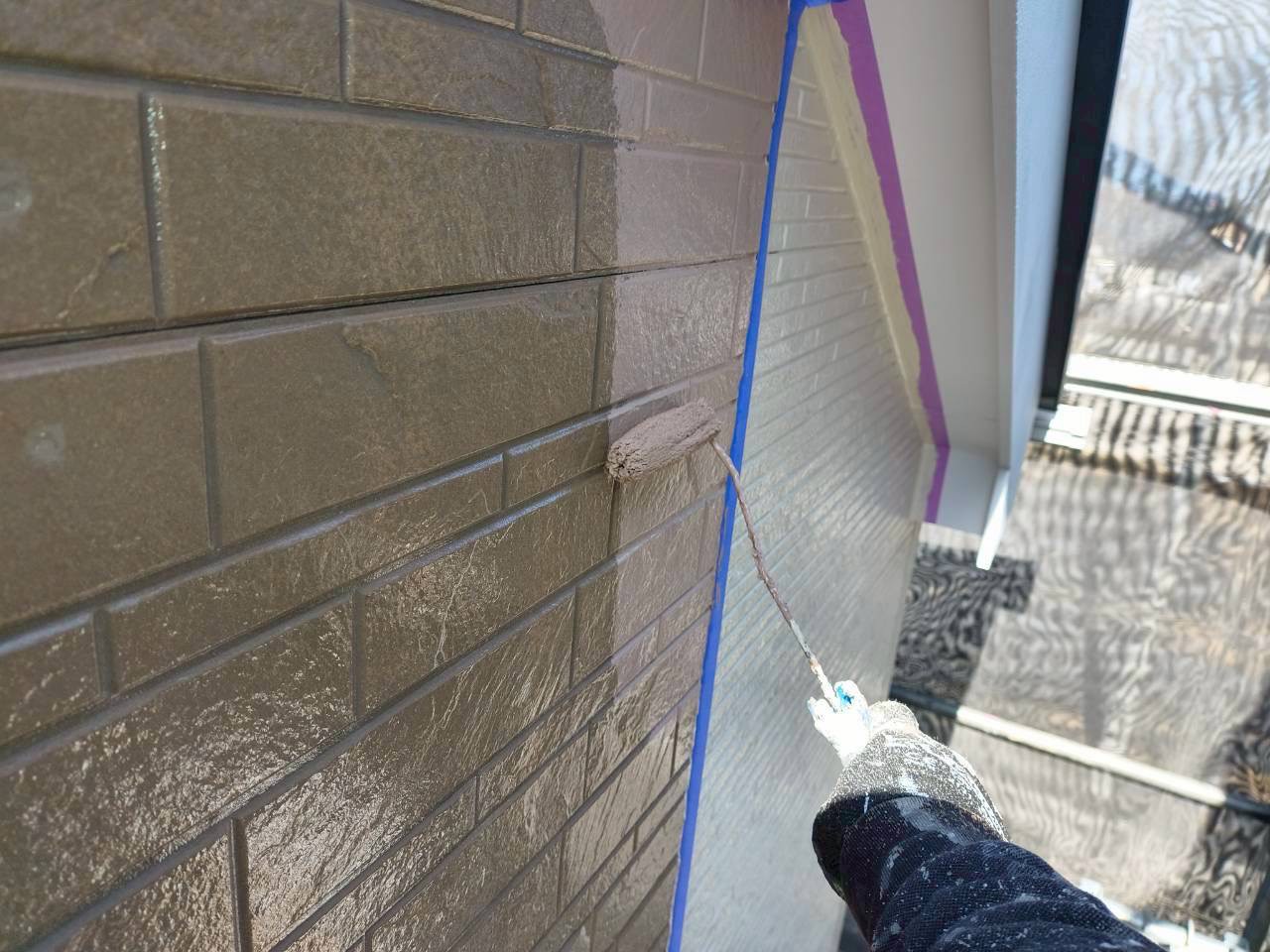 古くなった石目柄の外壁に中塗り塗装中